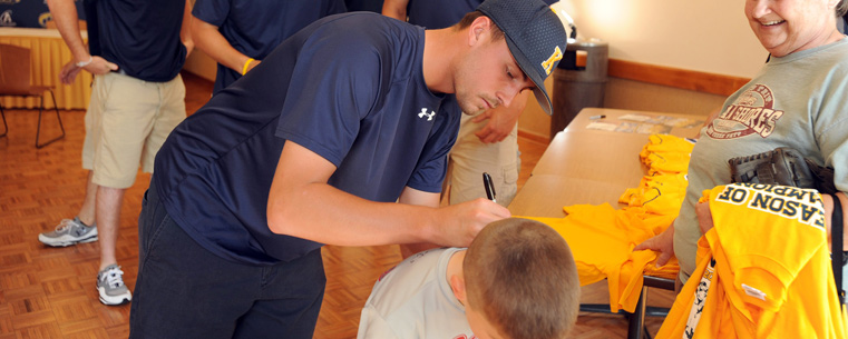 <p>Kent State baseball player David Starn signs the shirt of a young baseball player from Kent.</p>