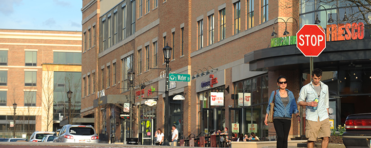 Students enjoy some of the new stores in College Town Kent, a pedestrian-oriented shopping, office and lifestyle center developed by Fairmount Properties and its partners. The 185,000-square-foot development in downtown Kent includes the new AMETEK and Davey Tree buildings. Seen in the background is the new Kent State University Hotel and Conference Center.