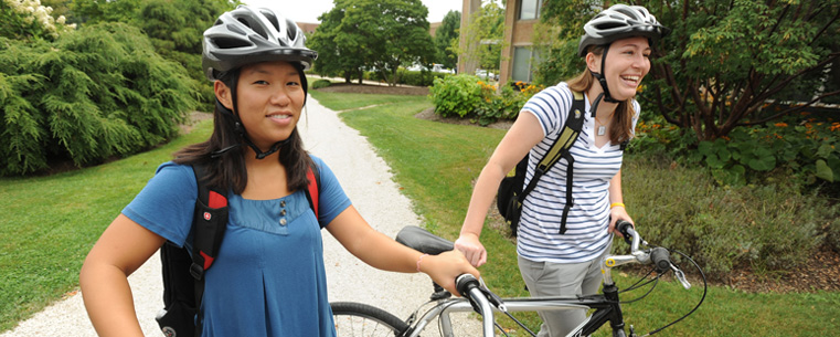 Two students with Flashfleet bikes behind the Library.