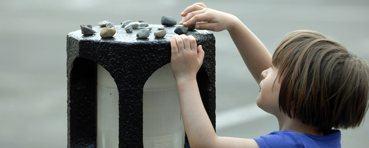 The daughter of a Kent State faculty member lays a stone on one of the concrete lanterns in the lot near Taylor Hall. The placing of stones on a memorial is a Jewish tradition.