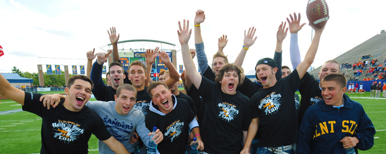 Fraternity members celebrate in the end zone after delivering the game ball.