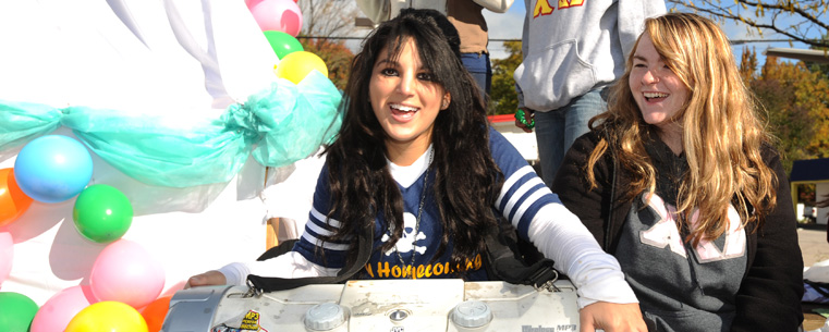 Sorority members ride their parade float down Main Street in front of the university.