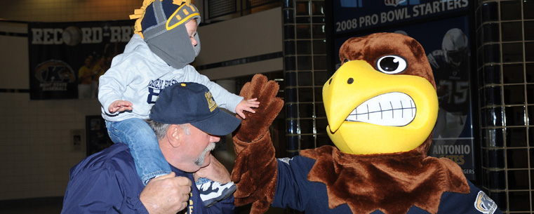 Flash, Kent State’s mascot, high-fives 18-month-old Christopher Errico as he and his grandfather Pasquale Christopher (and parent of Kent State football team member Andrew Christopher) arrive for the football team send-off event in the MAC Center.