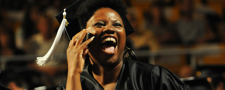 A summer 2011 graduate talks to her family on the phone during the commencement exercises.