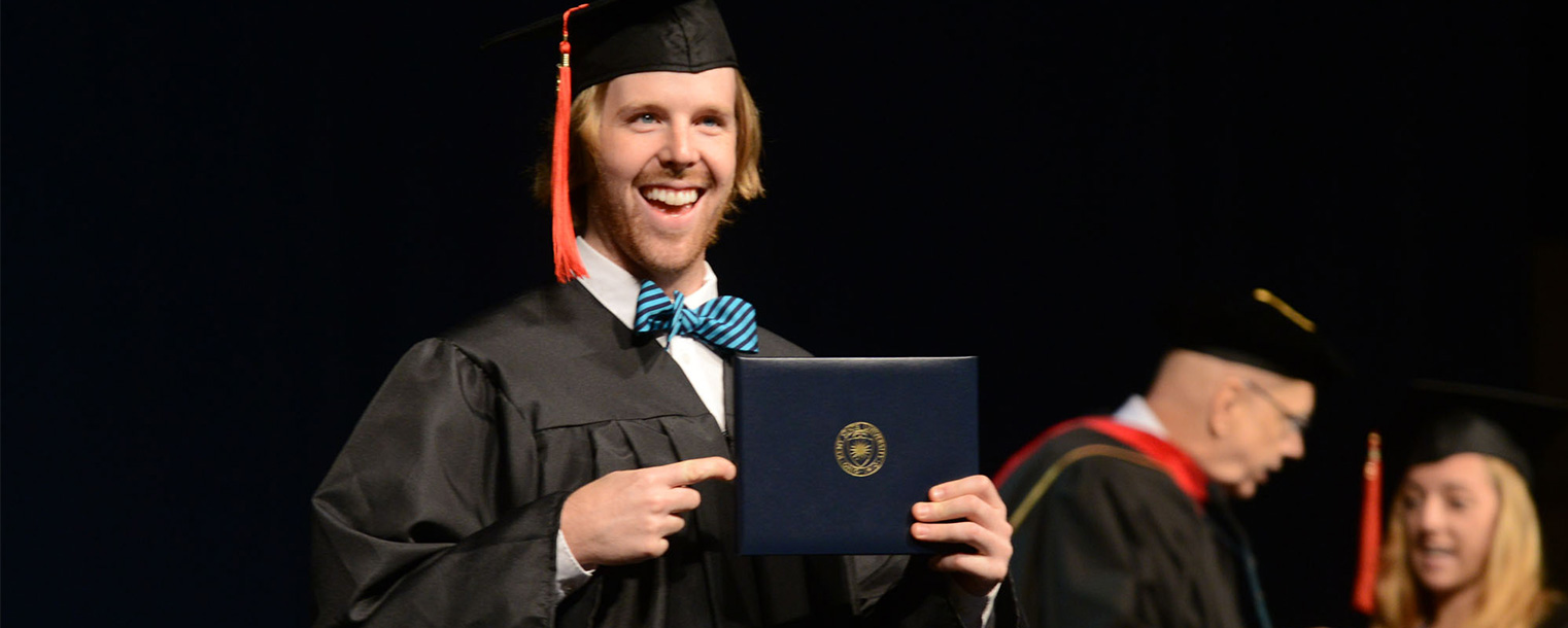 A summer 2013 graduate shows his diploma from Kent State to his family after walking the stage.