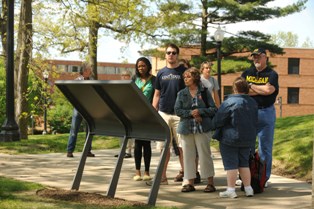 A group of people read one of the panel markers along the May 4 Walking Tour on the campus of Kent State University.