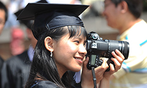 A Kent State graduating senior takes photos of her friends after commencement.